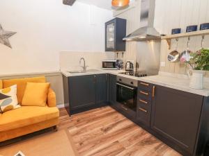 a kitchen with black cabinets and an orange couch in it at Teal Cottage in Leyburn