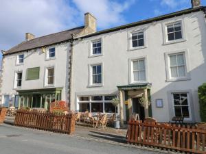 a white building with a wooden fence in front of it at Teal Cottage in Leyburn