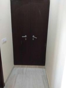 Una puerta negra en una habitación con suelo de baldosa. en OYO Naveen Residancy, en Gurgaon