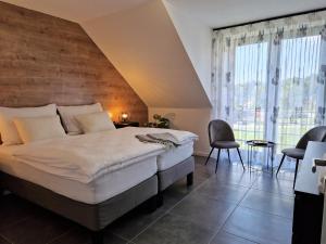 - une chambre avec un grand lit et une grande fenêtre dans l'établissement CHALET HOUBOVÝ VRCH, à Horní Planá