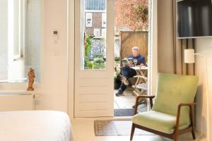 an older man sitting at a table outside a door at De DroomBoutique - Goud & Zilver Suites in Gorinchem