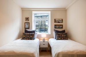2 camas individuales en una habitación con ventana en 8 Booth Court en Glossop
