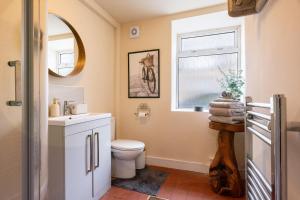 a bathroom with a toilet and a sink and a window at 8 Booth Court in Glossop