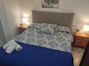 1 dormitorio con 1 cama azul y 2 mesitas de noche en Casita La Playa, en Málaga