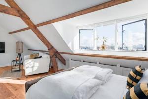 Un dormitorio con una cama blanca y dos ventanas. en BBWestduin, en La Haya