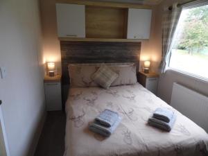 a bedroom with a bed with two towels on it at Stag Lodge in Great Yarmouth