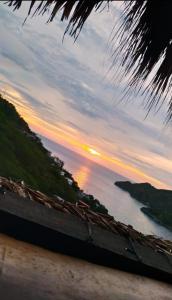 uma vista para o oceano ao pôr-do-sol a partir de uma praia em Hostal Casa Horizonte em Taganga