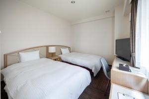 Court Hotel Niigata في نيغاتا: غرفه فندقيه سريرين وتلفزيون