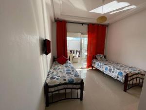 two beds in a room with red curtains at appartement chic et ensoleillé ola blanca 2 in Dar Hamida