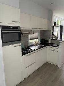 a kitchen with white cabinets and a stove top oven at Knus chalet Heidebloem Recreational purposes only in Putten +3 photos