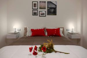 ein Schlafzimmer mit einem Bett mit roten Kissen und Blumen darauf in der Unterkunft Metro Bengasi Torino Lingotto Premium location - eXpress traveler spazioso - Grand Maison in Turin
