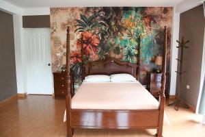 a bedroom with a canopy bed with a floral wallpaper at Zoila's Suite Escape in Nuevo Tingo