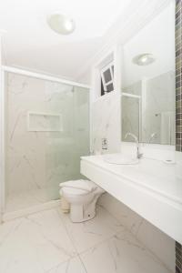 Baño blanco con aseo y lavamanos en Pousada Marbella Inn, en Búzios