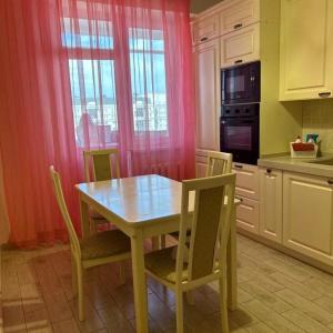 een keuken met een houten tafel en stoelen en een keuken met roze gordijnen bij ЖК Нурсая in Astana