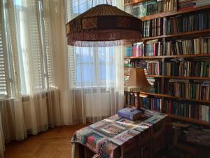 una stanza con tavolo e lampada di fronte a una libreria di White Hotel Guesthouse a Zugdidi