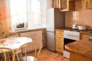 eine Küche mit einem weißen Kühlschrank und einem Tisch mit Stühlen in der Unterkunft Нью-Йорк in Petropawlowsk