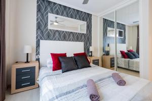 een slaapkamer met een bed met rode kussens en een spiegel bij Beautiful, quiet apartment with heated pool AP236 in San Miguel de Abona