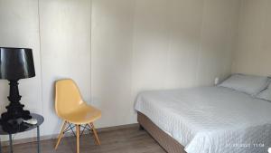1 dormitorio con 1 cama y 1 silla amarilla en Relajate y disfruta, en Santa Cruz de la Sierra