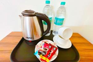 a tray with a coffee maker and two bottles of water at Hotel Ganga Ashoka - Rishikesh in Rishīkesh