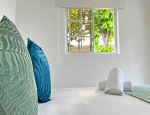 Habitación con 2 almohadas azules y ventana. en Zaba Beach House en San Andrés