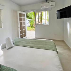 Cama grande en habitación blanca con ventana en Zaba Beach House, en San Andrés