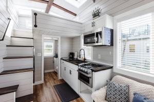 cocina con armarios blancos y fogones en Royal sands tiny home en Apple Valley