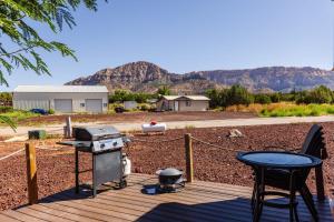 a grill and a table on a deck with a view at Ruby Red Tiny Home in Apple Valley