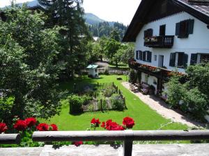 un patio verde con flores rojas junto a un edificio blanco en Melchambauer, en Maria Alm am Steinernen Meer