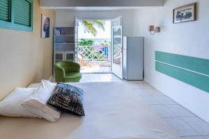 - une chambre avec un lit et une chaise verte dans l'établissement Villa Sable et Colibris, à Sainte-Luce