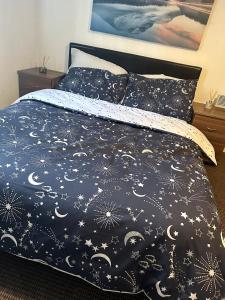 a bed with a black comforter with stars and moons at Unparalleled convenience! Luxury in Manchester