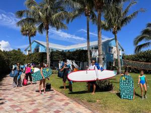 a group of people holding a surfboard in front of a house at Dual En-Suite Corner Unit - Sunrise Views in Fort Pierce +33 photos