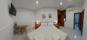 a bedroom with a bed and a desk and a television at Hostal Dulcinea in Madrid