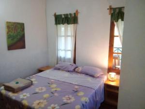 una camera da letto con un letto con lenzuola viola e una finestra di La Laurina Casa de Campo Hotel/Hospedaje a Villa Lonca