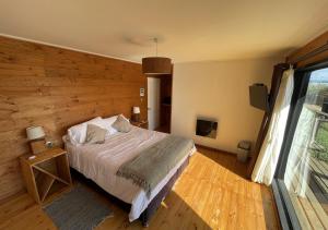 PelluhueにあるHotel Puerto Madera by DOT Boutiqueの木製の壁のベッドルーム1室(ベッド1台付)