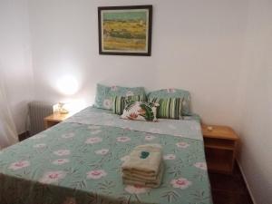 a bedroom with a bed with a green comforter and pink flowers at La Laurina Casa de Campo Hotel/Hospedaje in Villa Lonca