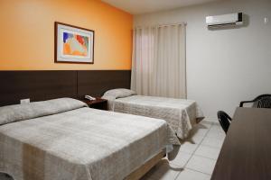 a hotel room with two beds and a table at Attiê Park Hotel in Uberlândia