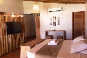 a bedroom with a bed and a television in it at Rancharia Charme Beach - Pé na Areia in Atins