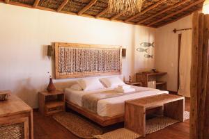 um quarto com uma cama grande e uma cabeceira em madeira em Rancharia Charme Beach - Pé na Areia em Atins