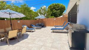 a patio with chairs and tables and an umbrella at Main House 3 Bed 2 Bath & Guest House 1 Bed 1 Bath in Miami