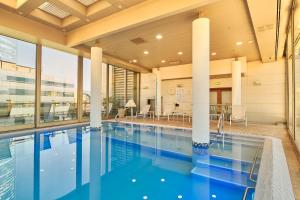 a swimming pool in a large building with columns at Plaza El Bosque Ebro in Santiago