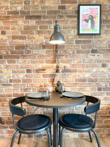 un tavolo e due sedie di fronte a un muro di mattoni di Red Rock Apartments - mit Parkplatz, Küche und Netflix a Treviri