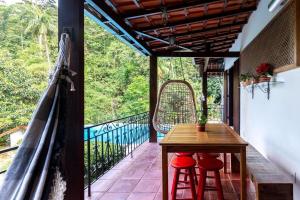 a balcony with a wooden table and two red stools at CurtaTere piscina lareira pet friendly jardim in Teresópolis