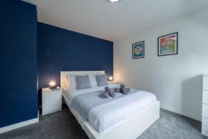 1 dormitorio con 1 cama grande y pared azul en Spacious 5-bedroom home perfect for large groups en Polesworth