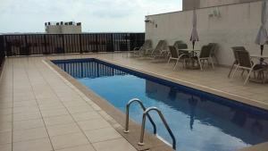 a swimming pool with chairs and a table next to a building at Nobile Flat Particular G07 in Brasilia