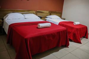 duas camas num quarto com lençóis vermelhos e toalhas em Hotel Residencial Panamericano em David