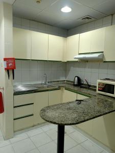 a kitchen with white cabinets and a granite counter top at Rovers Boys Hostel Dubai Near Gold Souq Metro in Dubai
