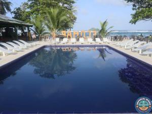 una piscina con tumbonas blancas y una playa en HOTEL IMPERIAL WOOD en Capurganá