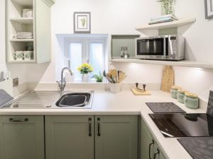 a kitchen with green cabinets and a sink and a microwave at Swallow's Nest in Gainsborough