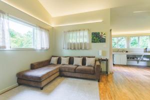 ein Wohnzimmer mit einer braunen Couch in einem Zimmer in der Unterkunft PonoMana Oasis's - Zen Cottage in Captain Cook