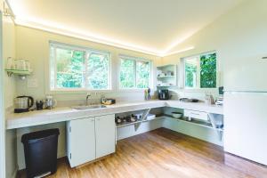 eine Küche mit weißen Theken und Fenstern und einem Kühlschrank in der Unterkunft PonoMana Oasis's - Zen Cottage in Captain Cook